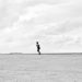 Black and white photo of a lone person running on a vast barren landscape in Natal, Brazil.